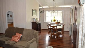 Una sala de estar con sofá, una mesa de comedor con sillas y una cocina con ventana.