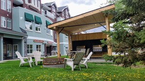 A covered outdoor seating area with Adirondack chairs and a fire pit, adjacent to a building with a sign reading "Sunset Resort Cannery." - Sunset Mountain Inn and Spa (Canmore)