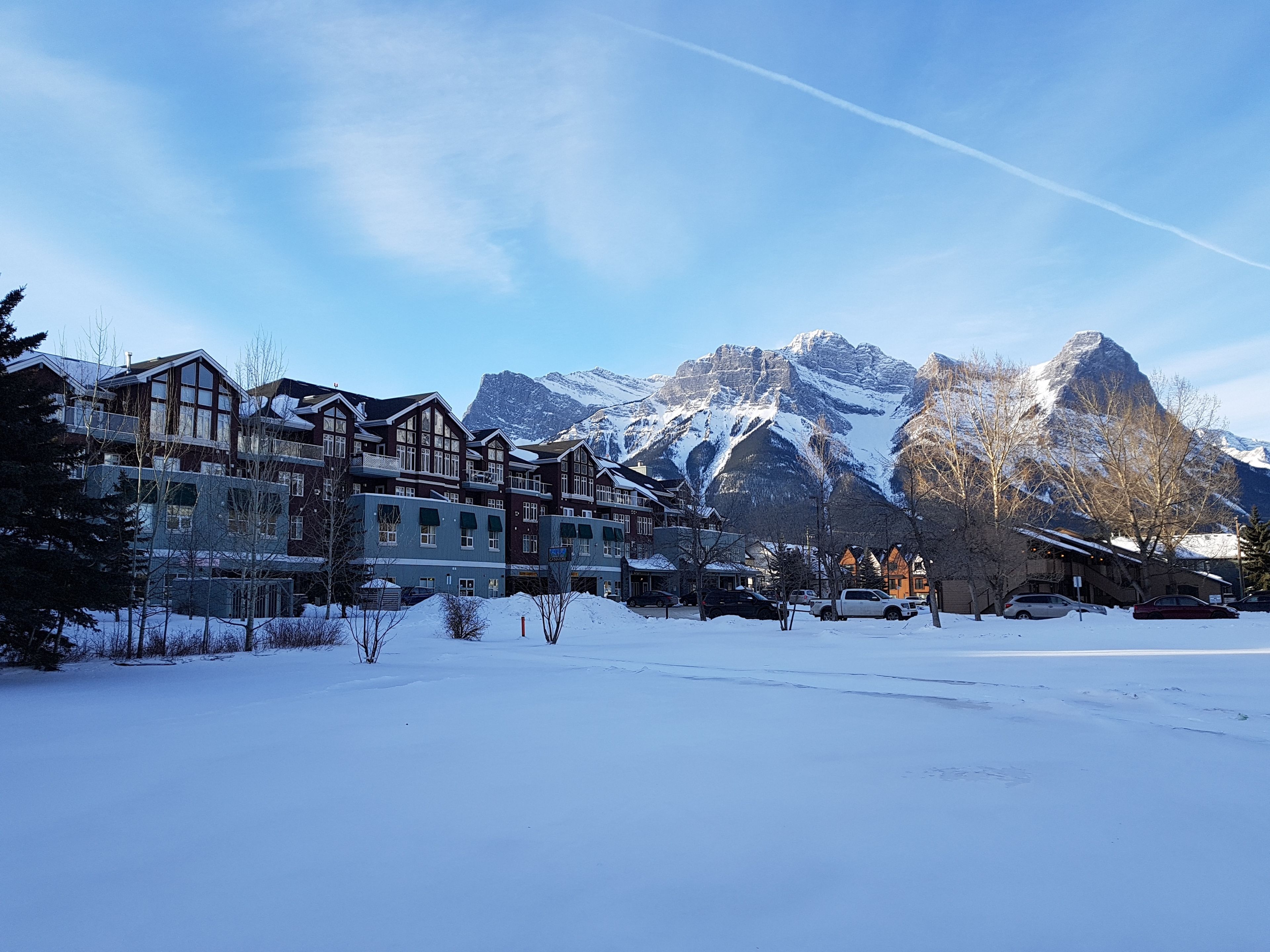 Een hotel met meerdere verdiepingen, grote ramen en uitzicht op besneeuwde bergen.