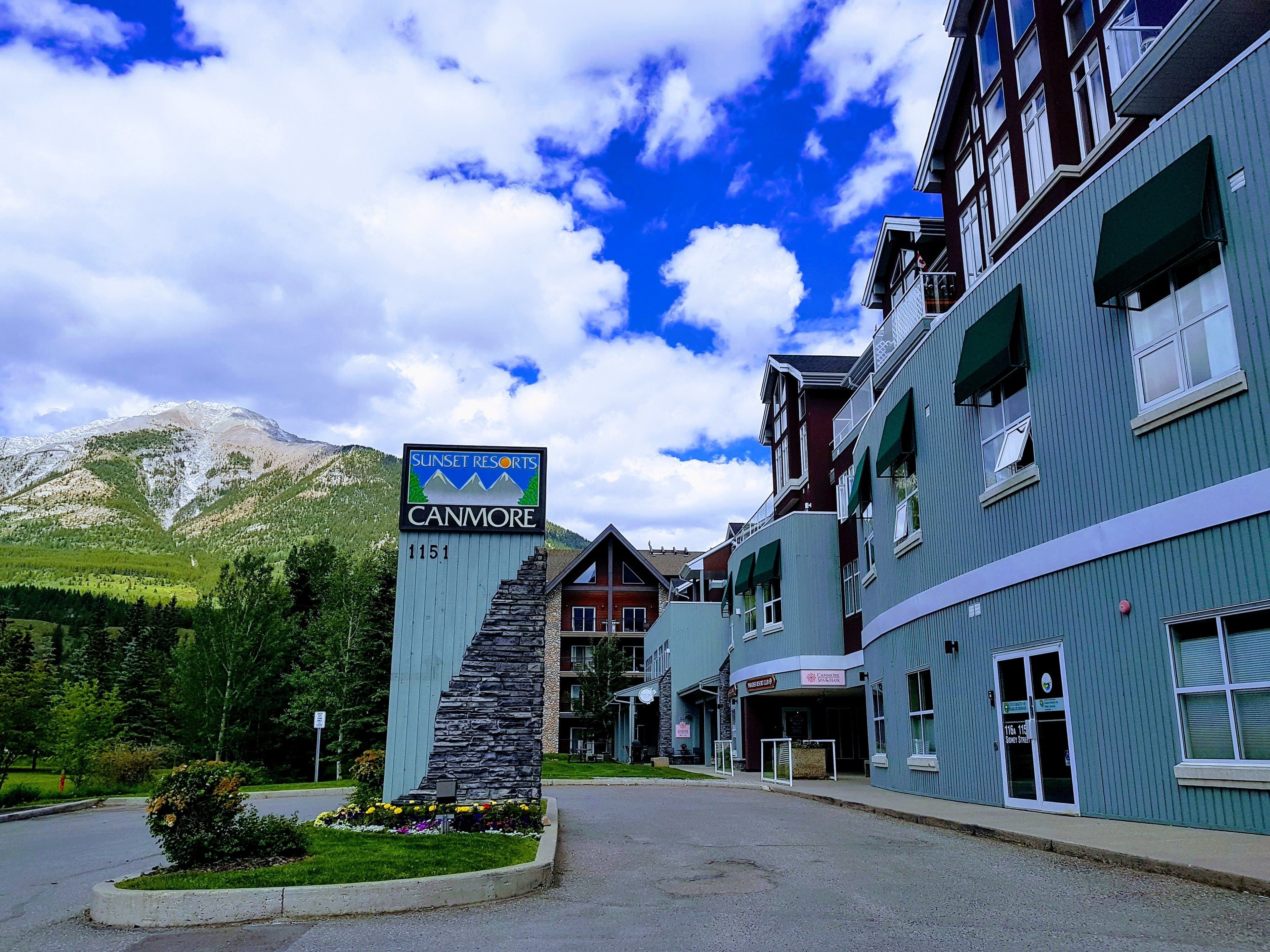 A hotel named 'Sunset Resorts' with a mountain backdrop, featuring a stone staircase entrance, a restaurant, and a ski lift visible in the background.