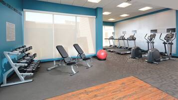 A gym with exercise equipment, a large window, and a blue wall.