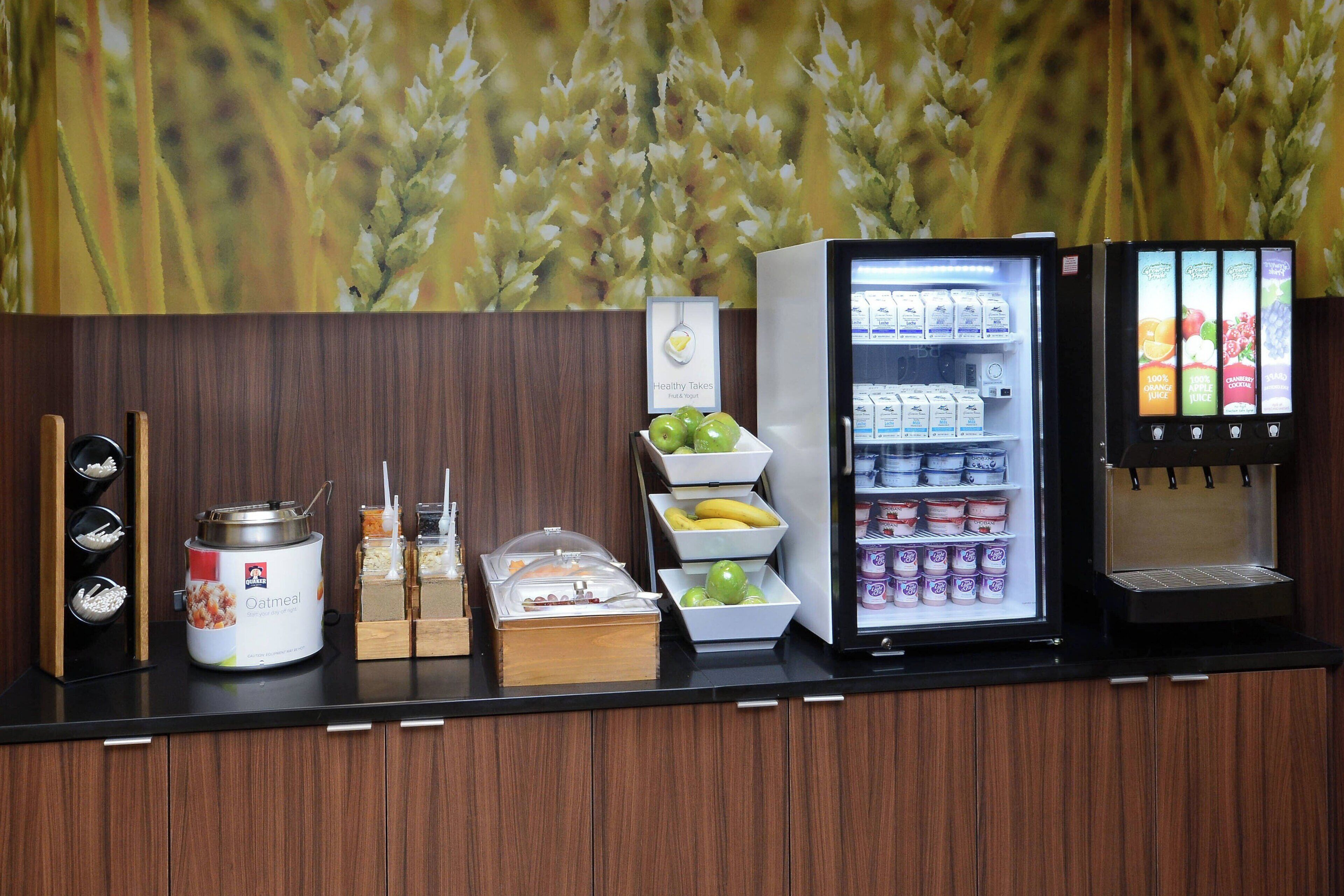 Un comptoir-buffet pour le petit-déjeuner, doté d’un présentoir réfrigéré, d’un distributeur de jus et de divers aliments, notamment des flocons d’avoine et des fruits.