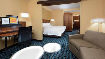 A hotel room with a bed, a desk with a chair, a sofa, and two small tables.