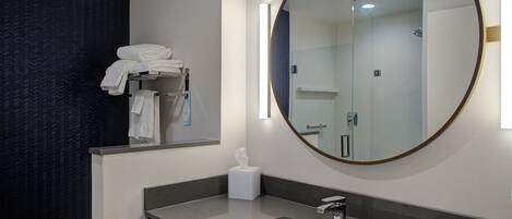 Une salle de bain moderne avec un grand miroir, un lavabo et un porte-serviettes.