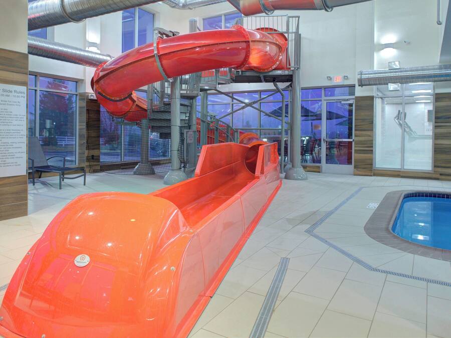 An indoor water slide area with a clear path and a pool at the end.