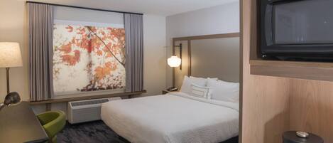 A hotel room with a bed, a desk, a chair, a television, and a large window with a floral view.