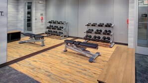 Ein Fitnessraum mit Bänken, Kurzhanteln und einer Langhantelbank.
