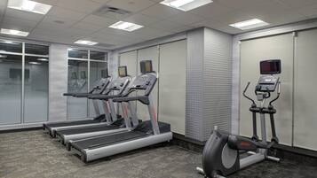 Un gimnasio con cintas de correr, elíptica y bicicleta estática.