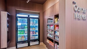 A corner market with two refrigerated beverage vending machines and shelves stocked with snacks and beverages.