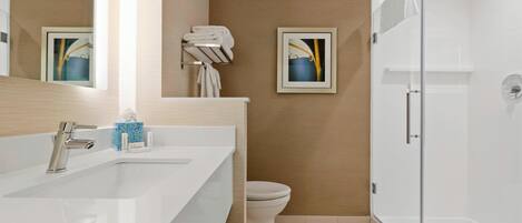 A modern bathroom with a white sink, a toilet, and a glass shower enclosure.