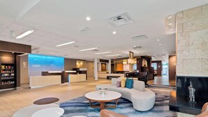 A modern hotel lobby with a reception desk, seating area, and a fireplace.