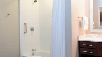 Un baño con bañera, ducha, inodoro y tocador con espejo.