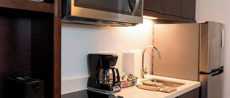 A modern kitchen with a built-in microwave, coffee maker, and a sink with a faucet.
