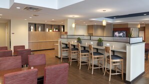 A modern restaurant with wooden furniture, a central island, and a high ceiling.
