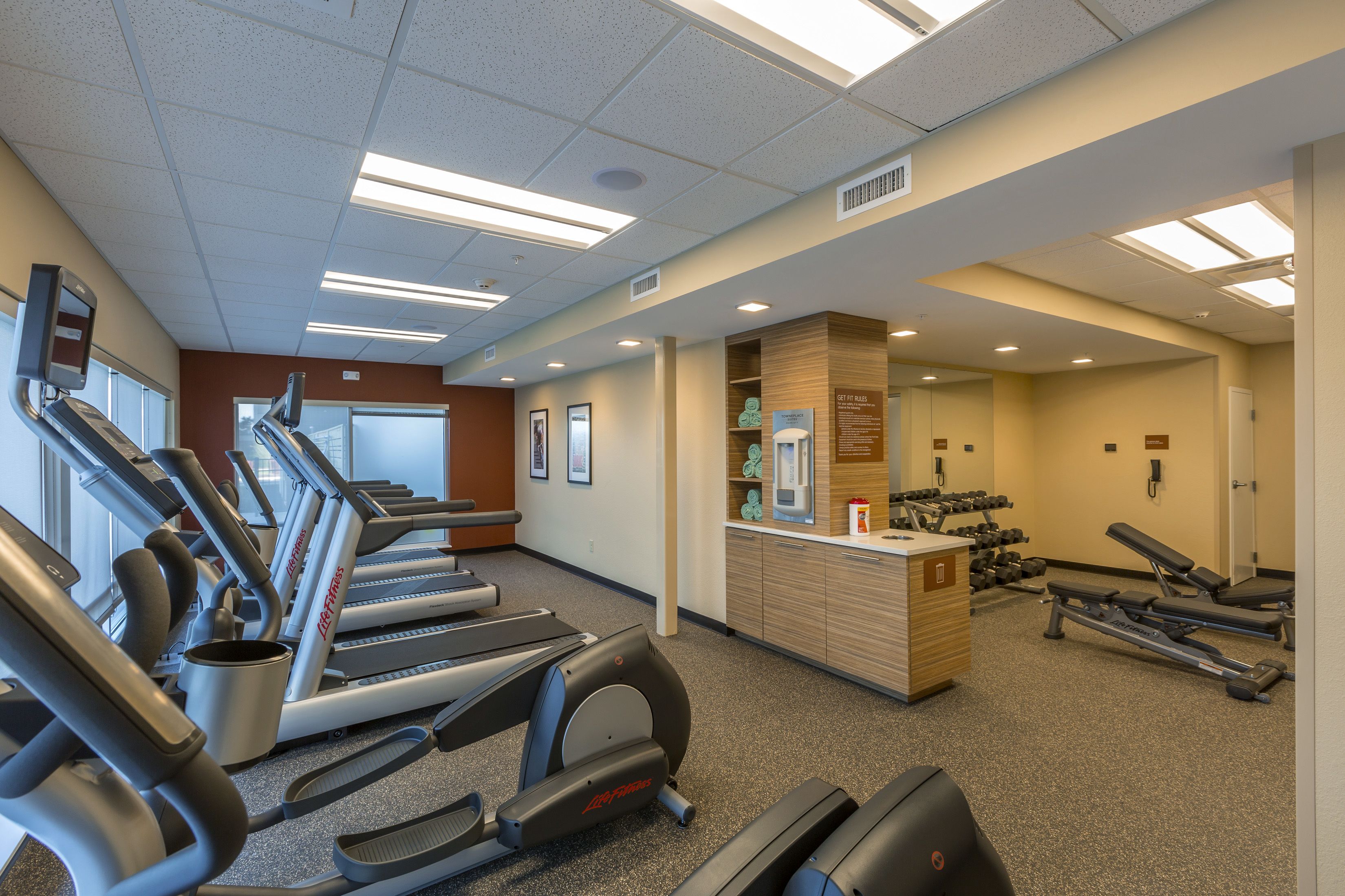A gym with treadmills, dumbbells, and benches.