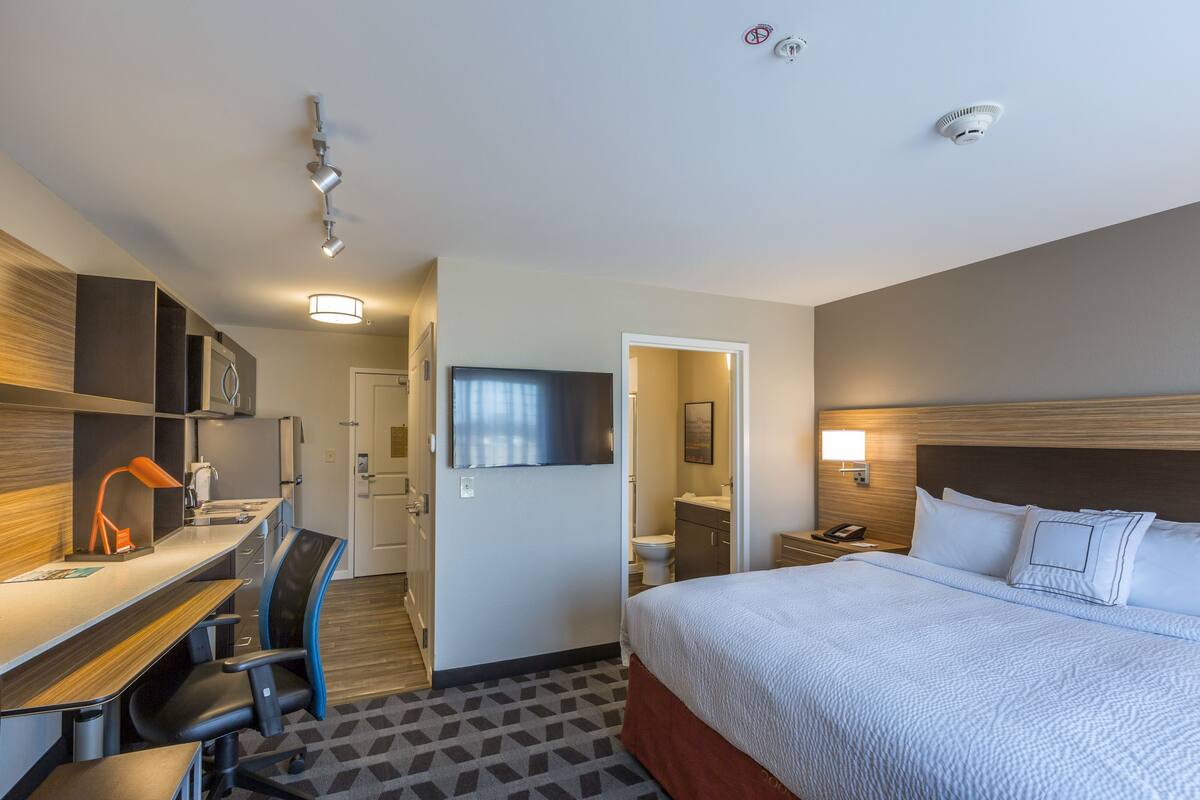 Ein Hotelzimmer mit Bett, Schreibtisch, Stuhl und Fernseher.