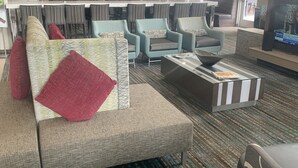 Un moderno vestíbulo de hotel con un sofá modular, sillones, una mesita de centro y un televisor.