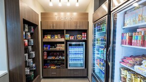 Zona de bebidas y snacks de autoservicio con productos refrigerados.