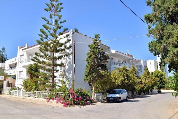 A white building with balconies, surrounded by trees and shrubs. - Hotel Anna Apartments (Gouves)