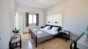 A bedroom with a bed, bedside tables, a nightstand, a potted plant, and a window with curtains. - Hotel Anna Apartments (Gouves)