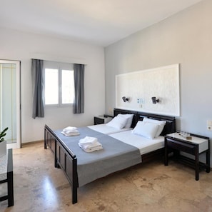 A hotel room with a bed, bedside tables, a window with curtains, and a wall-mounted light fixture. - Hotel Anna Apartments (Gouves)