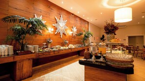 A buffet area with a wooden wall, decorative wall art, and various food items. - Beira Rio Palace Hotel (Piracicaba)