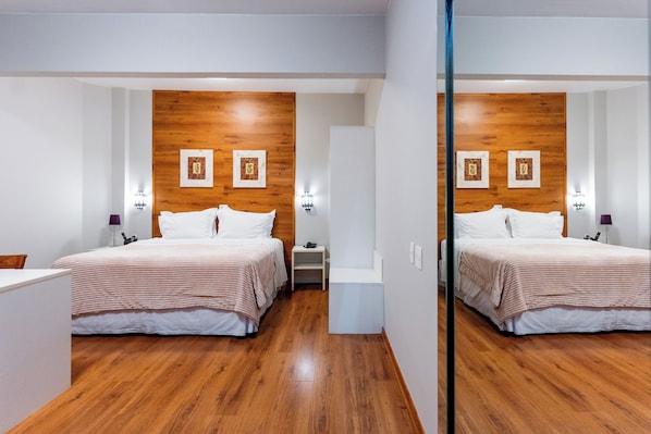 A hotel room with a wooden headboard, two bedside tables, a bed with white bedding, and a small nightstand. - Beira Rio Palace Hotel (Piracicaba)