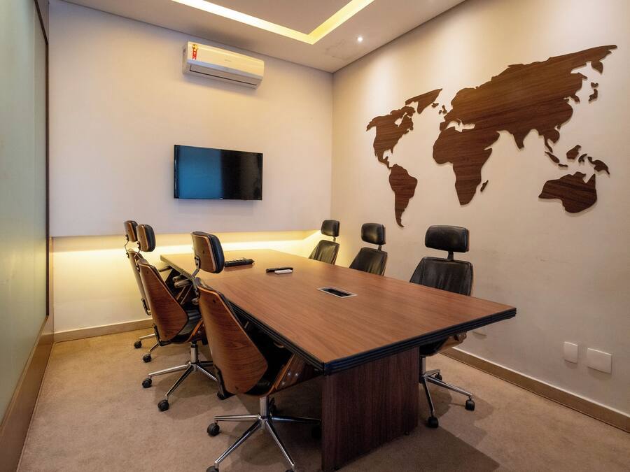 Un salón de conferencias con una mesa larga, seis sillas, un televisor de pantalla plana y un mapa del mundo en la pared.