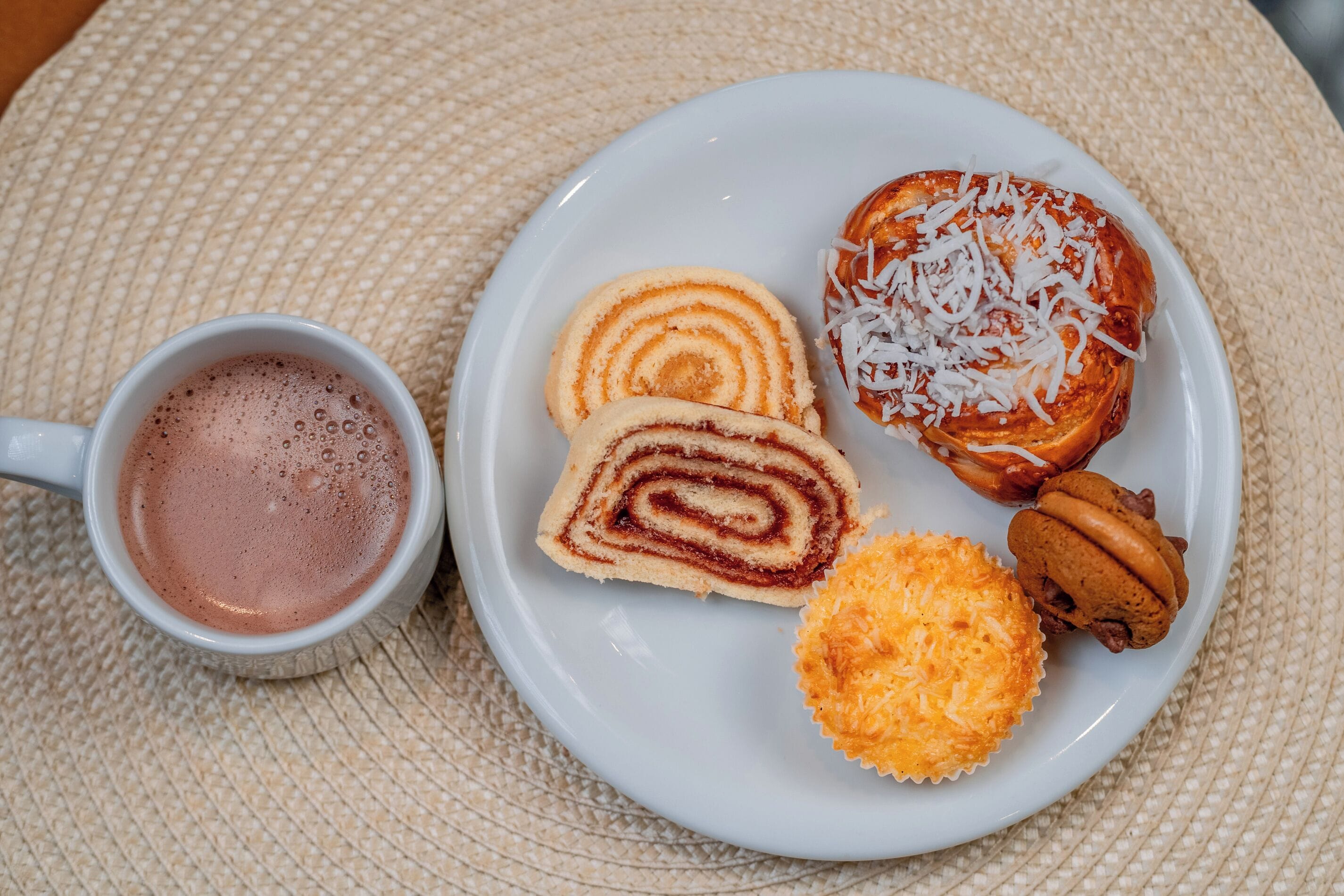 En tallrik med en bit kanelbulle, en chokladmuffin och en kaffekopp.