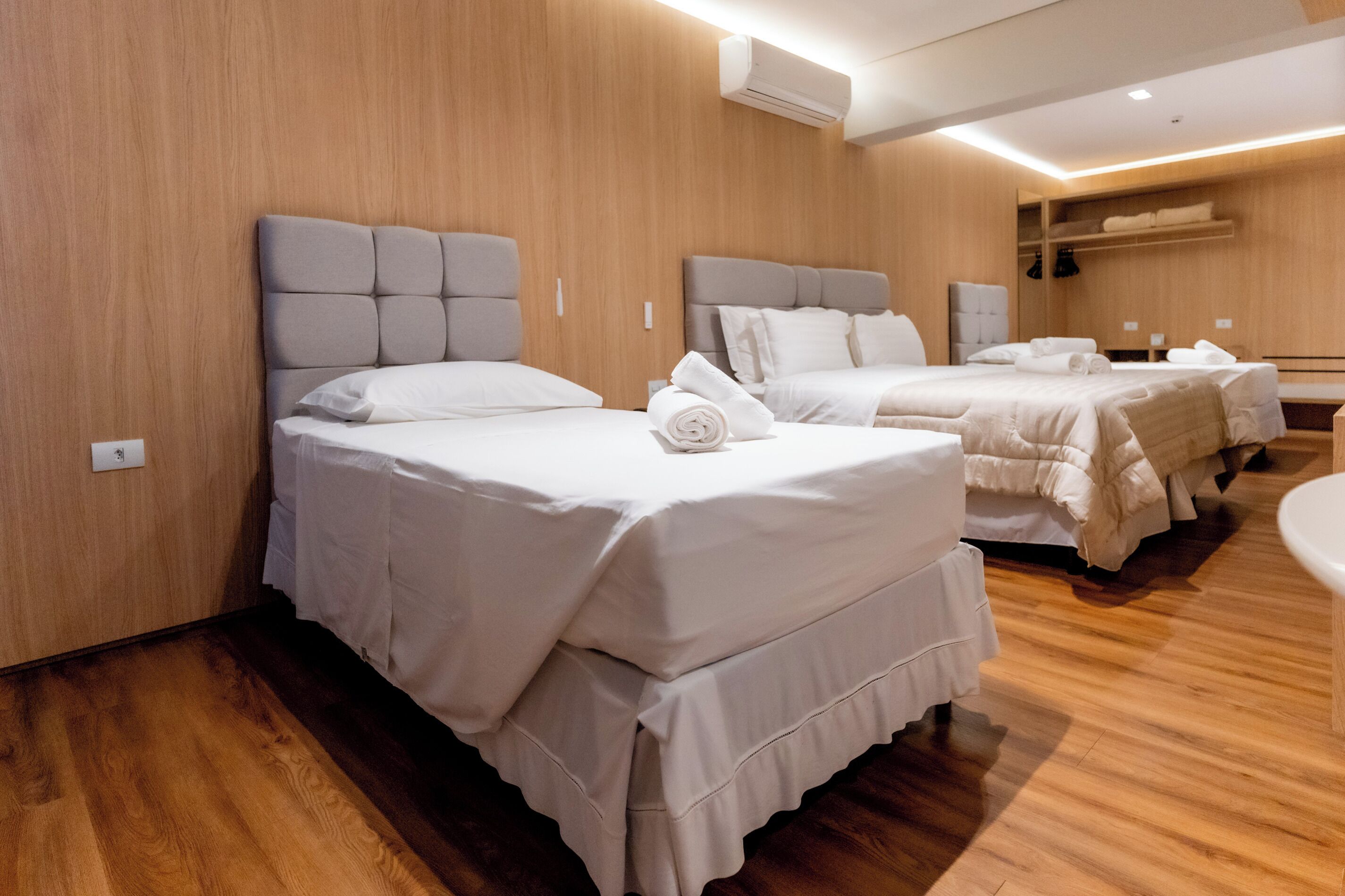 Una habitación de hotel con tres camas, paredes y piso de madera.