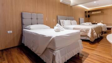 Una habitación de hotel con tres camas, paredes y piso de madera.