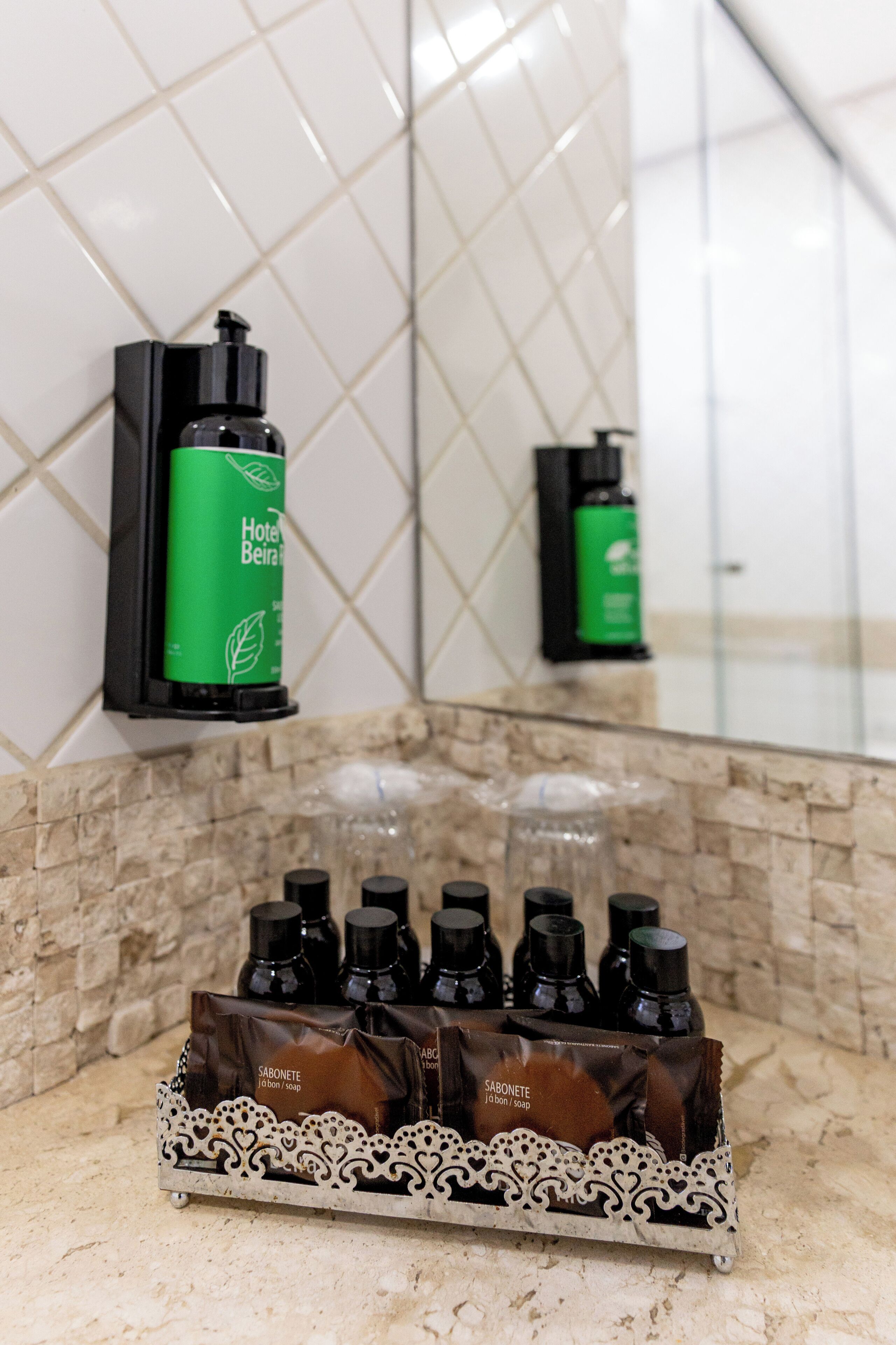 A bathroom with a tiled wall, a soap dispenser, and a soap dispenser stand.