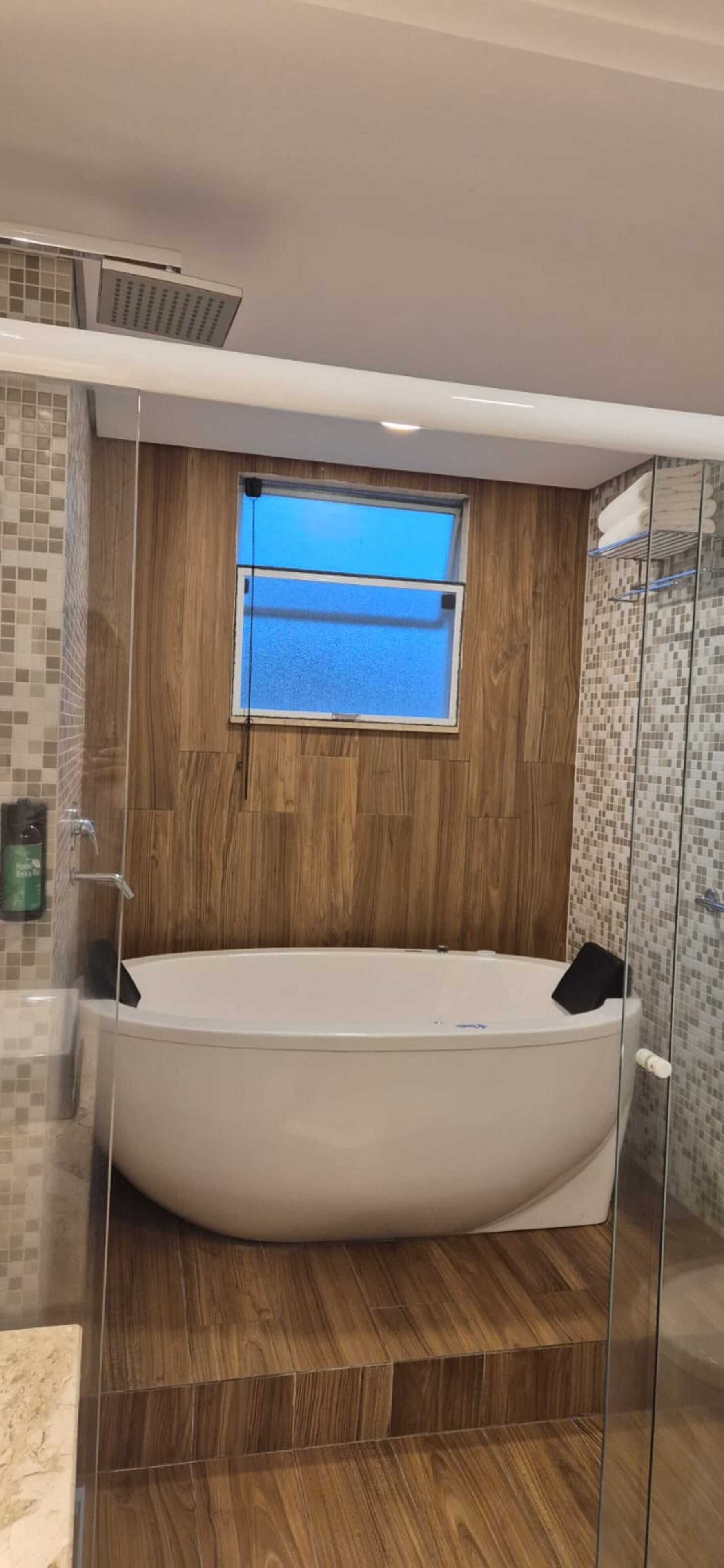A modern bathroom with a freestanding bathtub, a window, and a shower area.