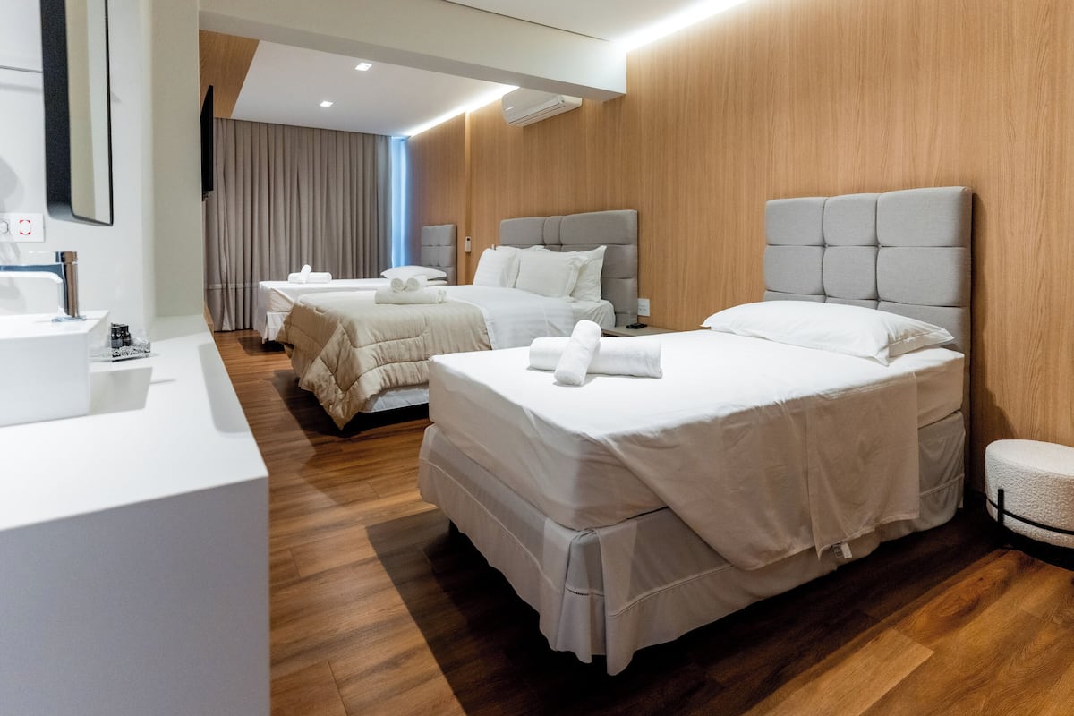 A hotel room with two beds, a bathroom, and a wooden wall.