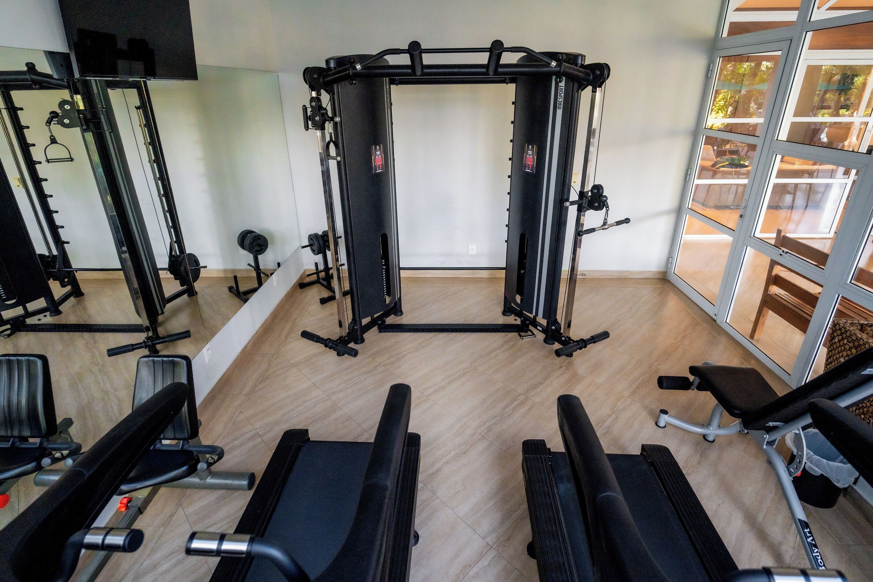 Ein Fitnessraum mit Trainingsgeräten, einer Klimmzugstange und einem Spiegel.