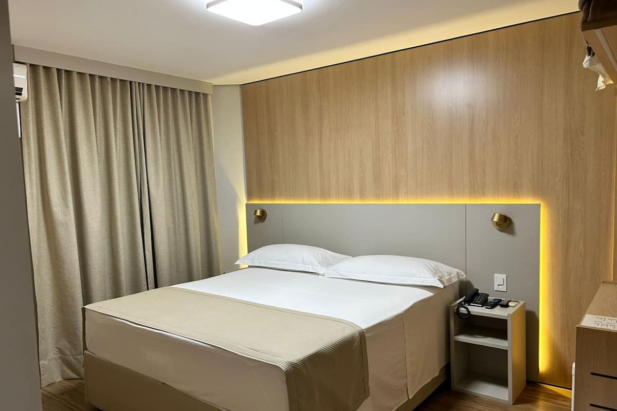 A modern hotel room with a large bed, bedside tables, and a built-in wardrobe.