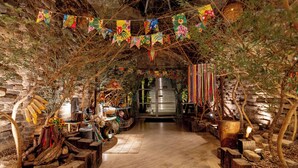An indoor setting with a wooden floor, stone walls, and a central aisle leading to a large, illuminated structure. - Beira Rio Palace Hotel (Piracicaba)