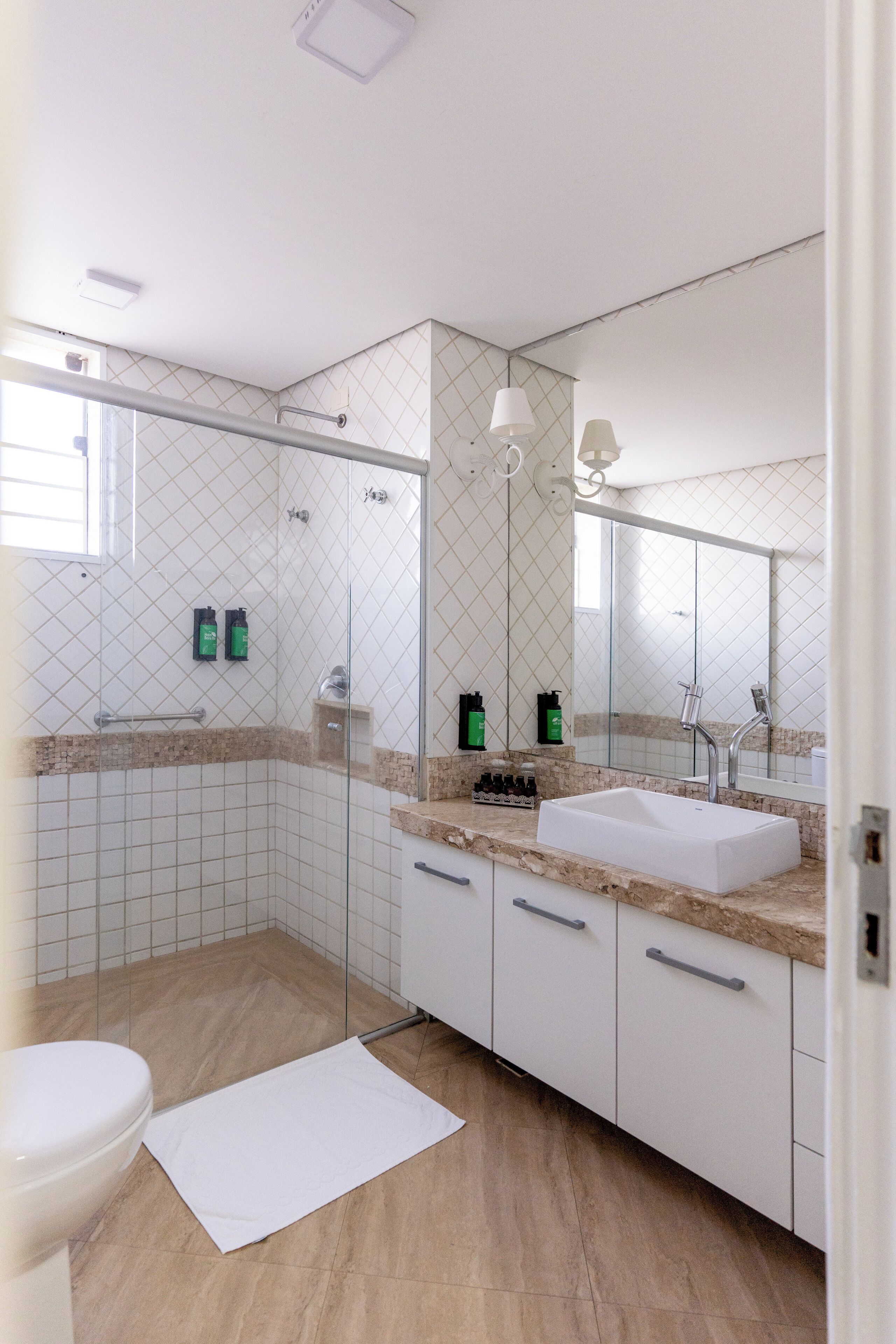 A modern bathroom with a glass shower enclosure, a white sink, and a large mirror.