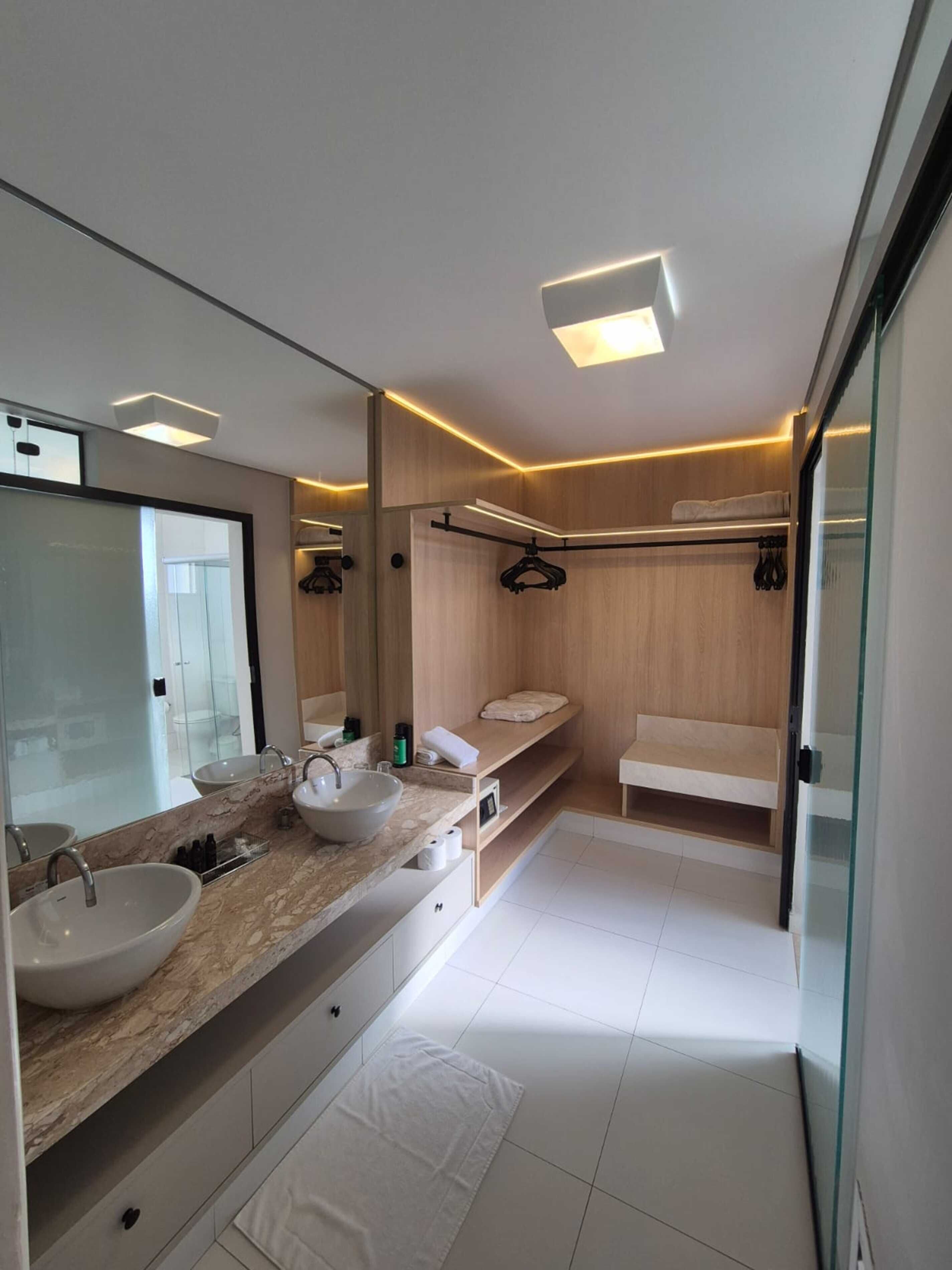 A modern bathroom with a large mirror, two sinks, and a walk-in shower.