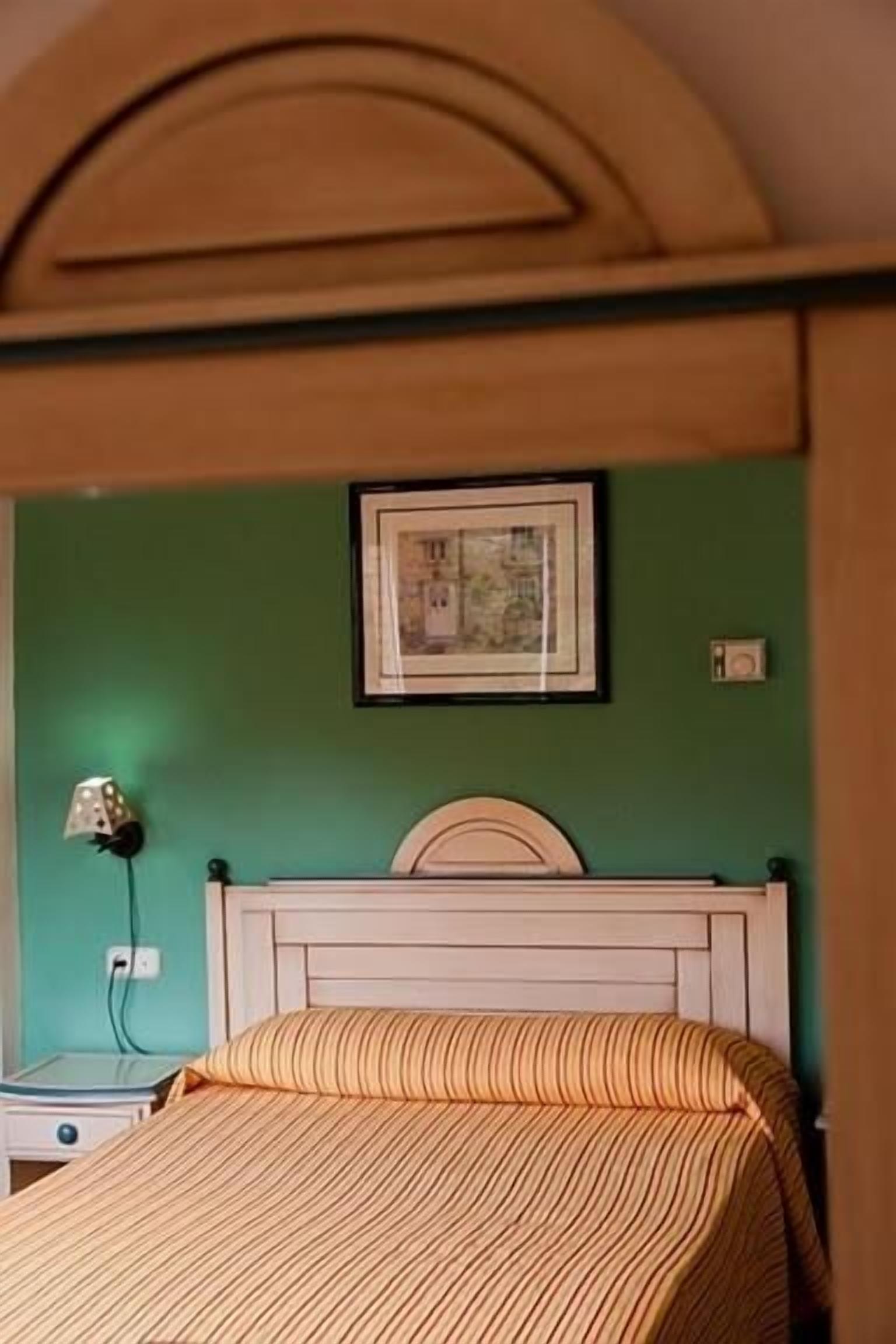 A bedroom with a bed, a nightstand, a lamp, and a framed picture on the wall.