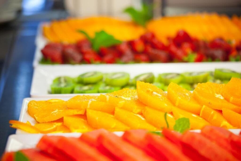 A buffet with various fruits including mangoes, oranges, and possibly strawberries.