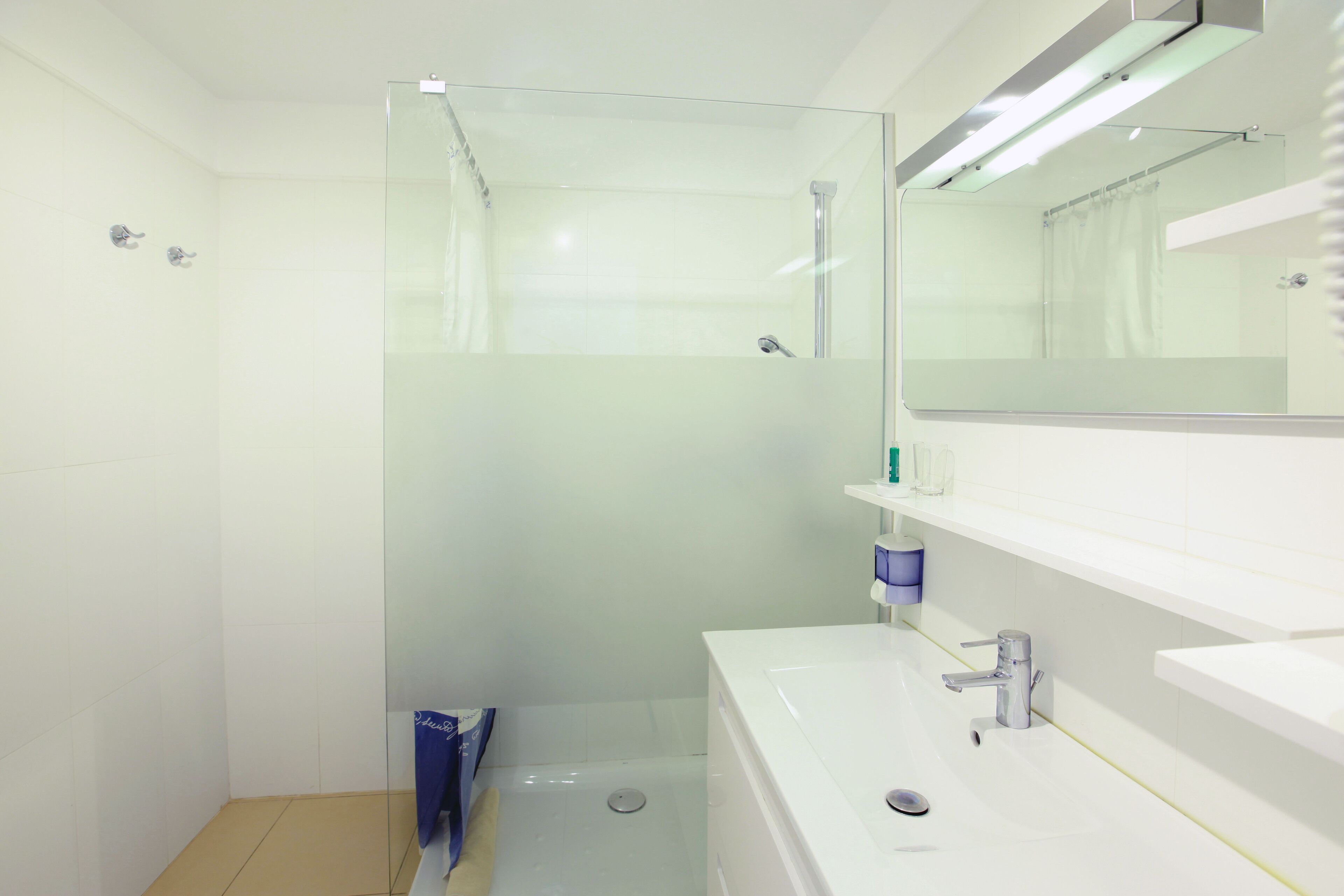 Un baño moderno con cabina de ducha de vidrio, un lavabo blanco y un espejo sobre él.