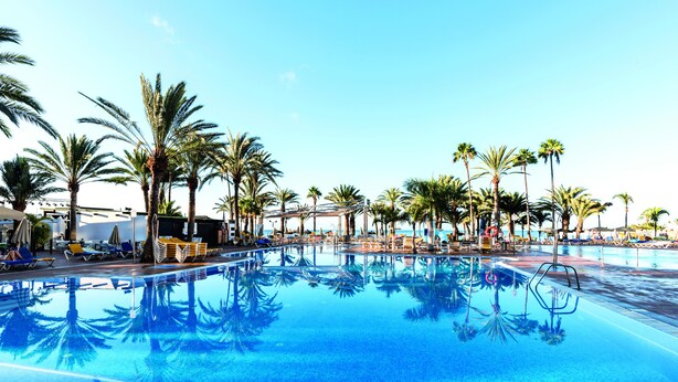 A large outdoor swimming pool surrounded by palm trees and lounge chairs. - Grupotel Tres Vidas (San Bartolomé de Tirajana)