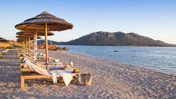 Privat strand, hvit sand, solsenger og parasoller