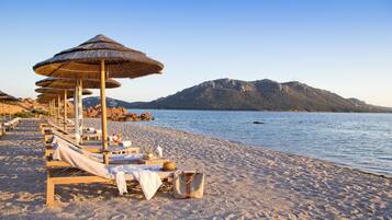 شاطئ خاص، رمال بيضاء، كراسي للتشمس، مظلات الشاطئ