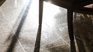 Un hall d’entrée avec un espace salon, une porte vitrée donnant sur l’extérieur et un sol carrelé.