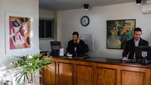 Un comptoir d’accueil avec deux employés, une horloge et des œuvres d’art accrochées aux murs.