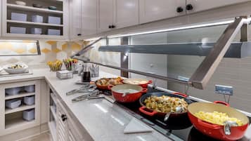 A buffet setup with various dishes, including a red pot of soup and a bowl of scrambled eggs.