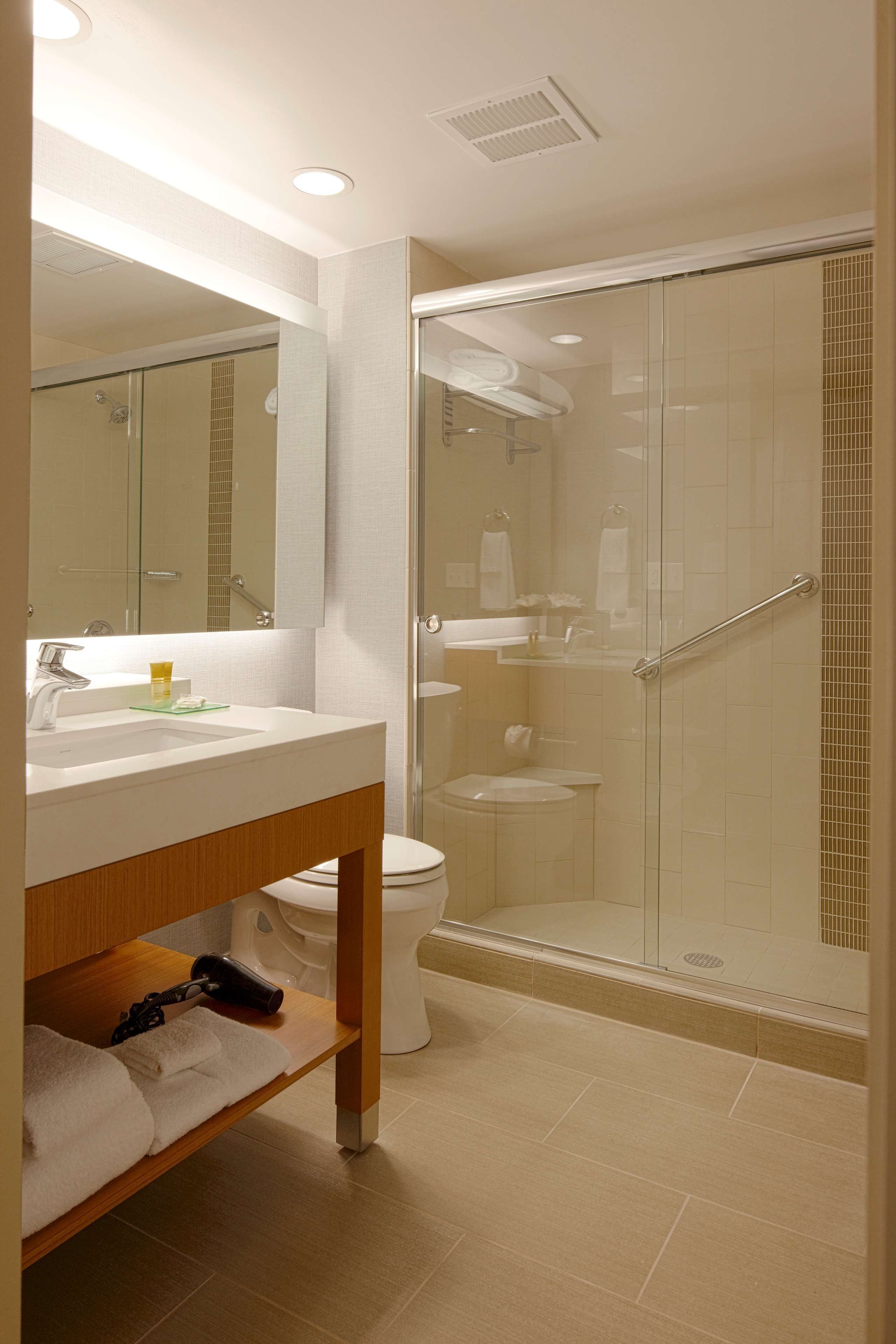 A modern bathroom with a glass-enclosed shower, a white sink, and a mirror above it.