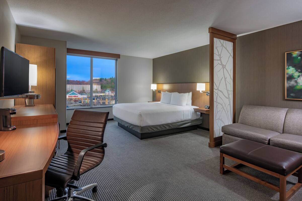 Habitación de hotel con cama, escritorio con silla, sofá y televisor.